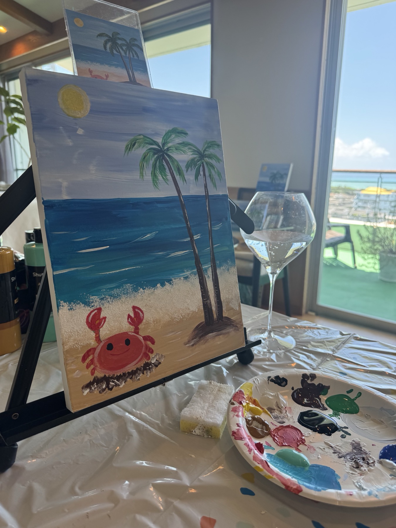 Palm tree and Little Crab painting in progress with paints and an ocean view