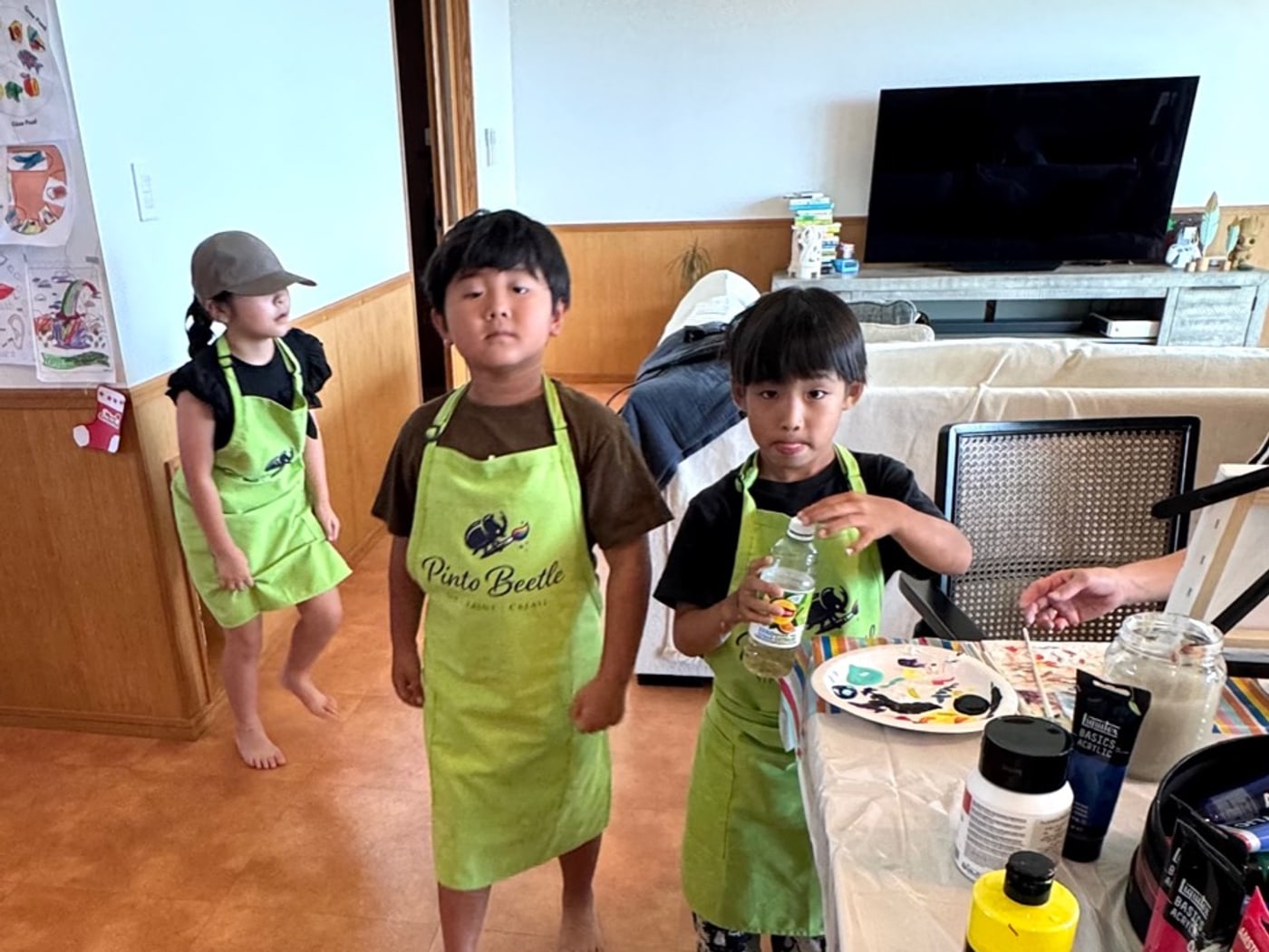 Young Pinto Beetle guests in green aprons during a relaxed painting session