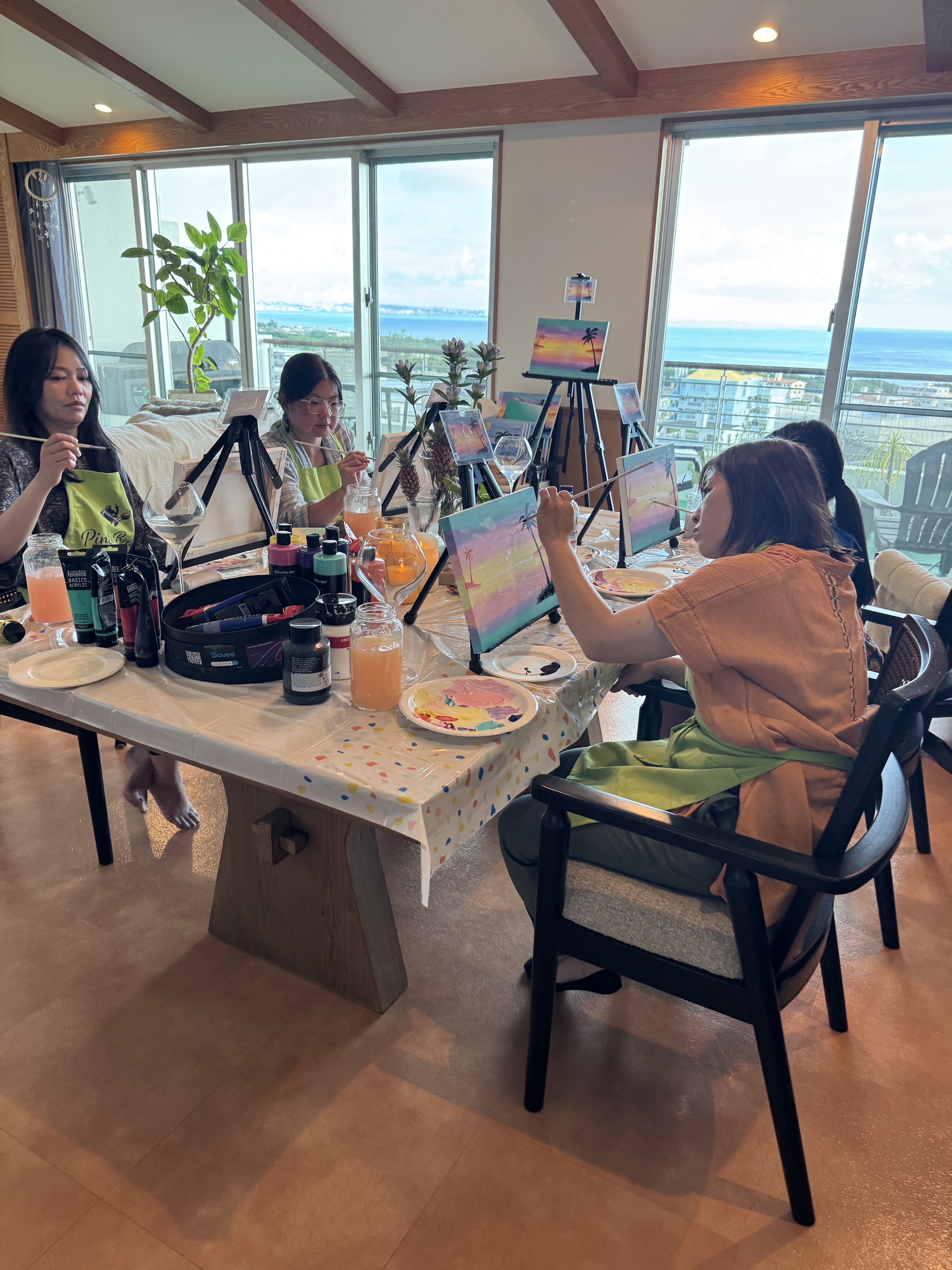 Pinto Beetle guests painting Sunset Paradise canvases around the ocean-view studio table